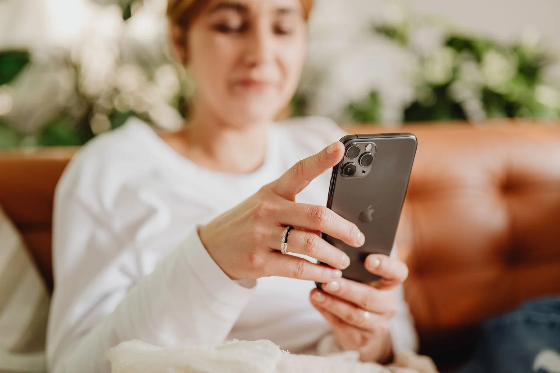 Frau auf dem Sofa sieht sich Inserate auf dem Smartphone an