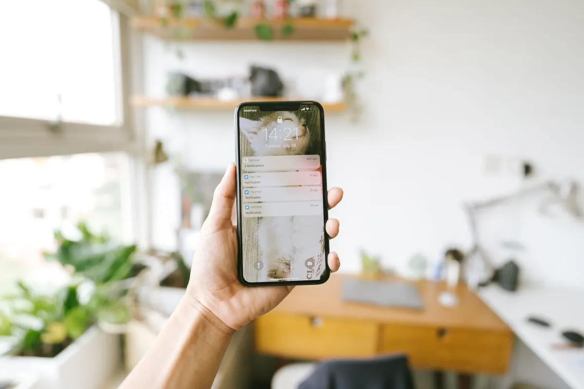 Hand hält ein Smartphone mit Benachrichtigungen auf dem Bildschirm